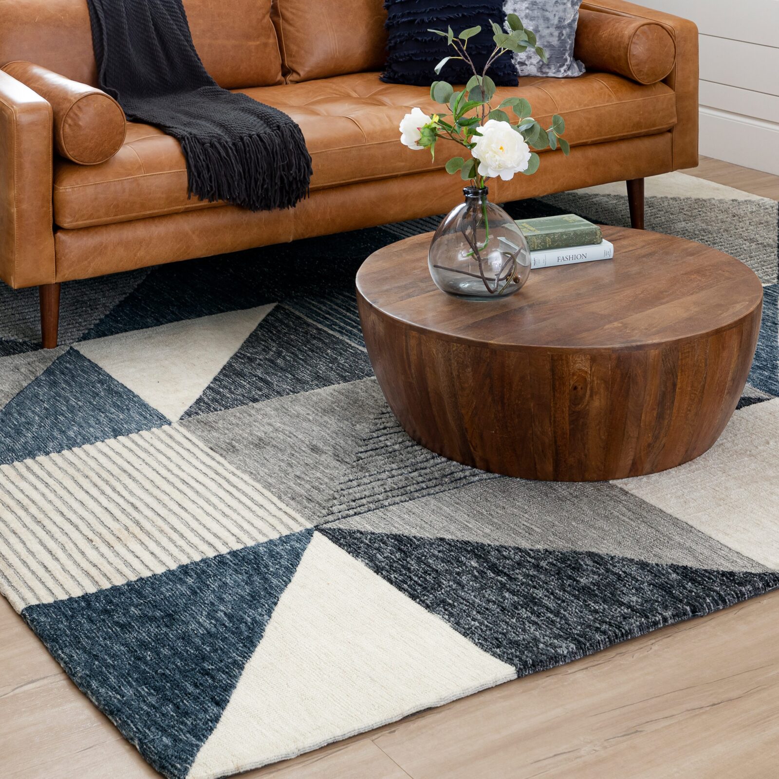 Living room with a leather sofa, round wood coffee table, and geometric patterned rug
