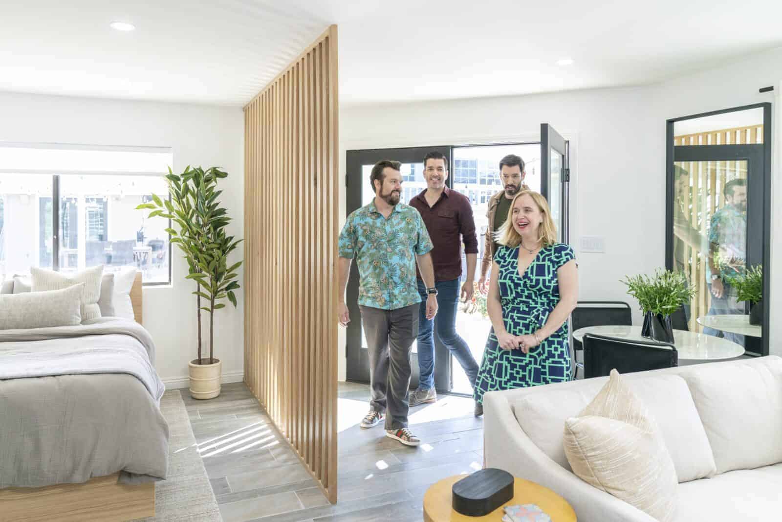 Group entering a bright, modern home with open layout, wood slat divider, and neutral decor
