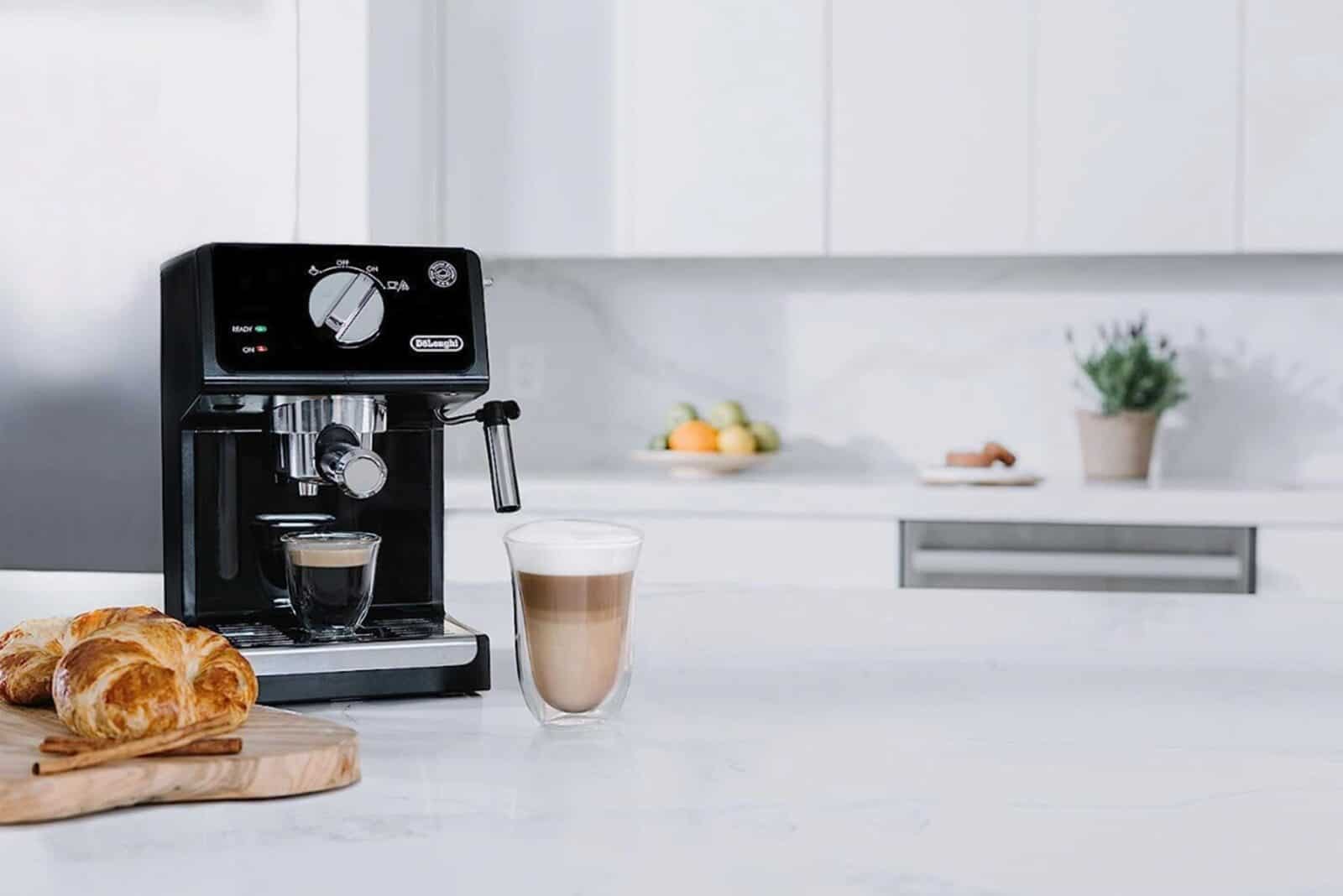 Espresso machine with coffee cups and croissants on kitchen counter