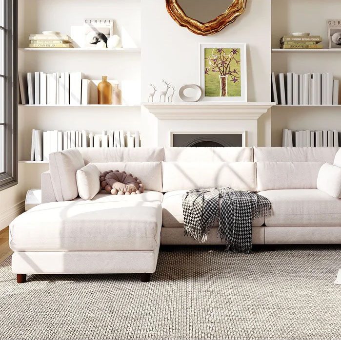 Bright living room with beige sectional sofa, houndstooth throw, and built-in shelves around a fireplace