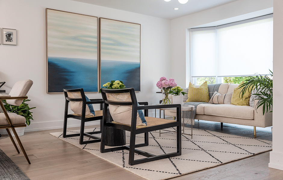 Modern living room with abstract ocean artwork, black chairs, neutral sofa, and green accents