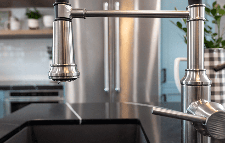 Close-up of a modern stainless steel kitchen faucet over a black countertop
