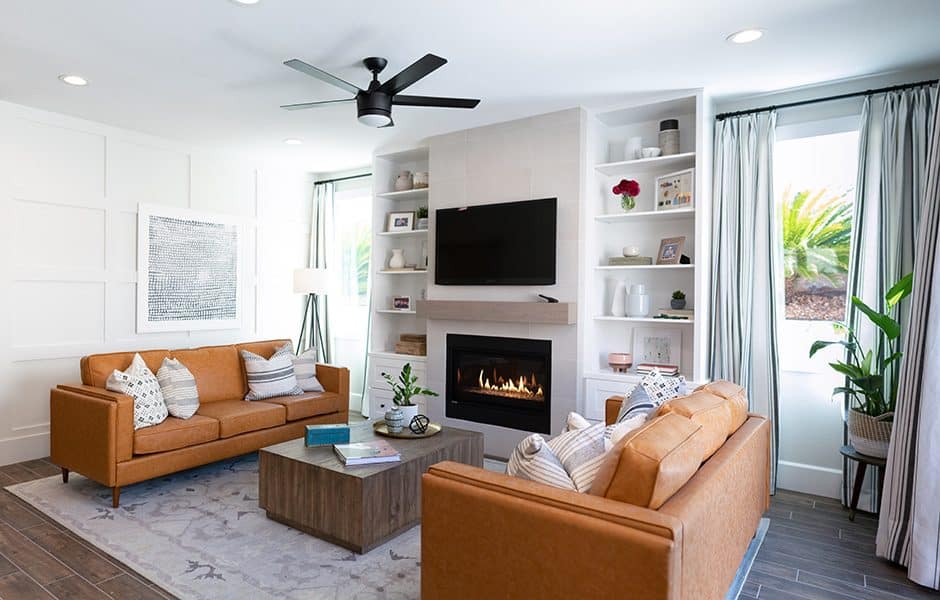 Modern living room with tan sofas, a fireplace, built-in shelves, and natural light