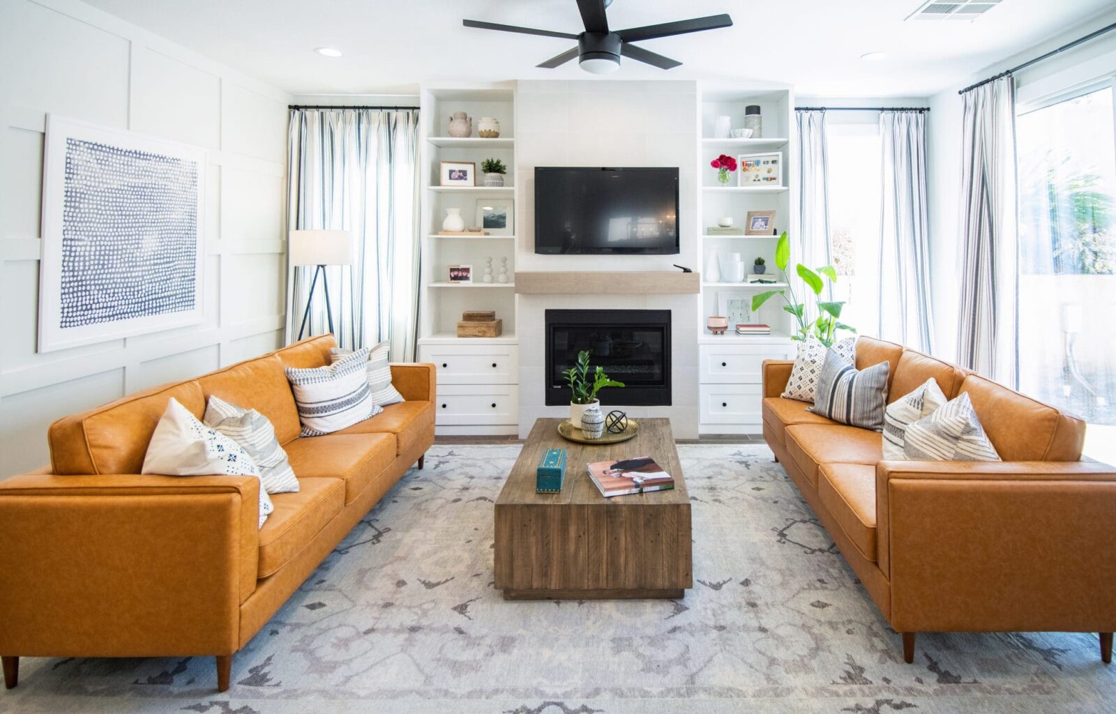 Modern living room with orange leather sofas, built-in shelves, and wall-mounted TV