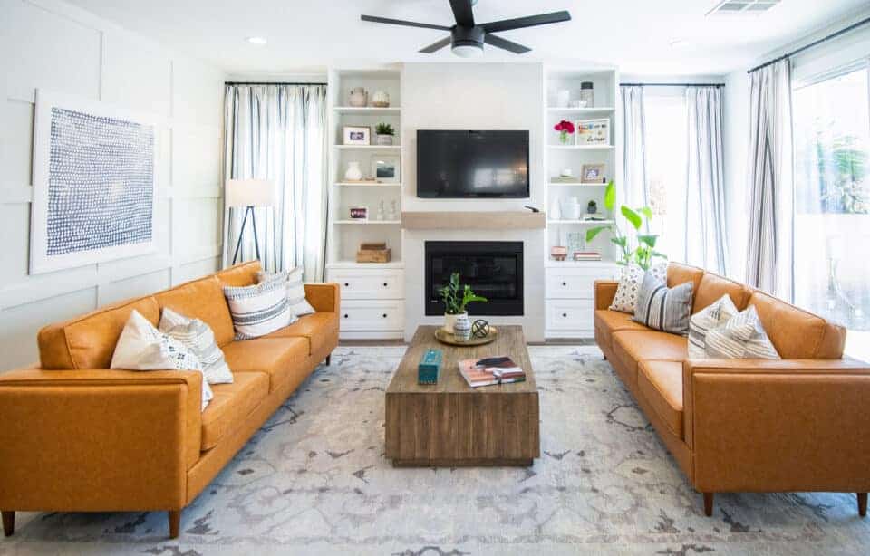 Modern living room with orange leather sofas, built-in shelves, and wall-mounted TV