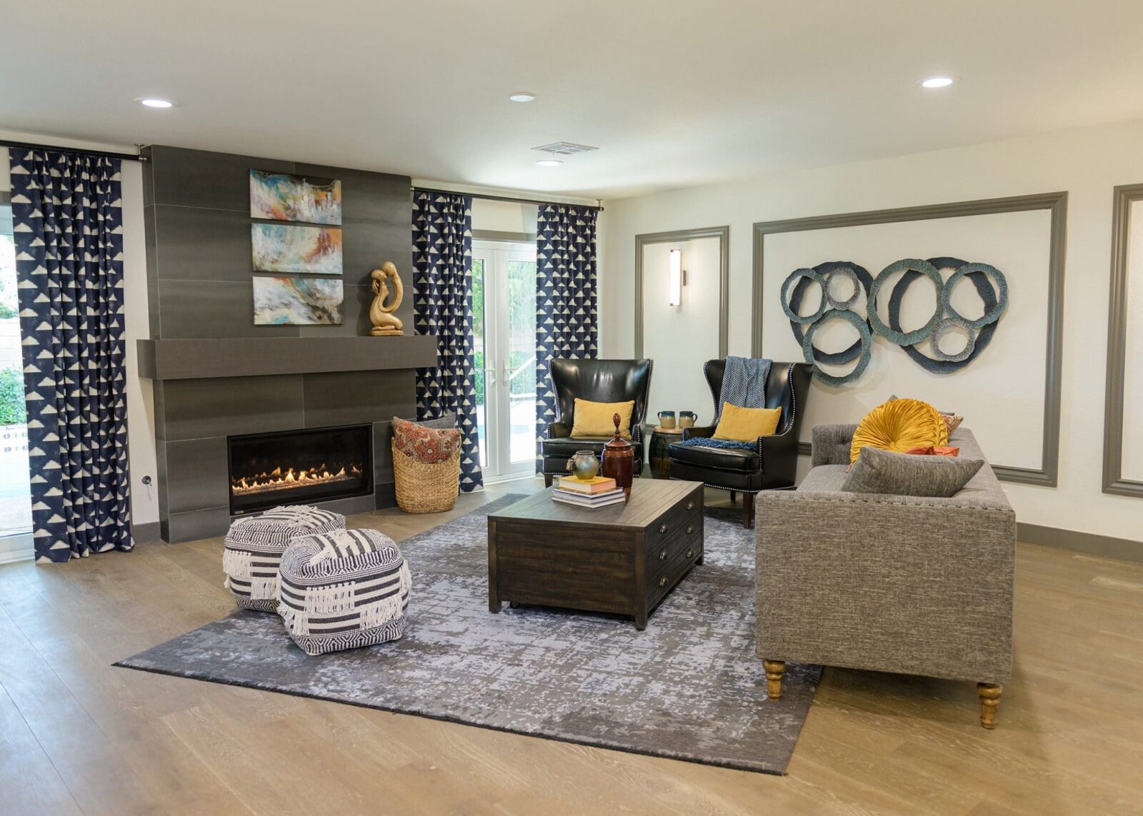 Contemporary living room with gray sofa, black leather chairs, geometric curtains, and a modern fireplace