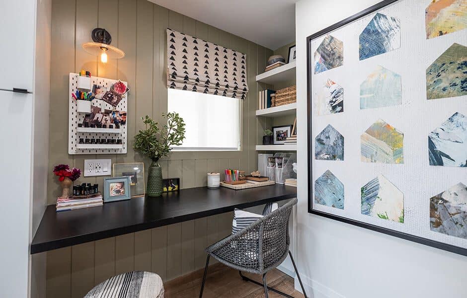 Compact home office with a black desk, woven chair, wall organizer, and decorative shelving.