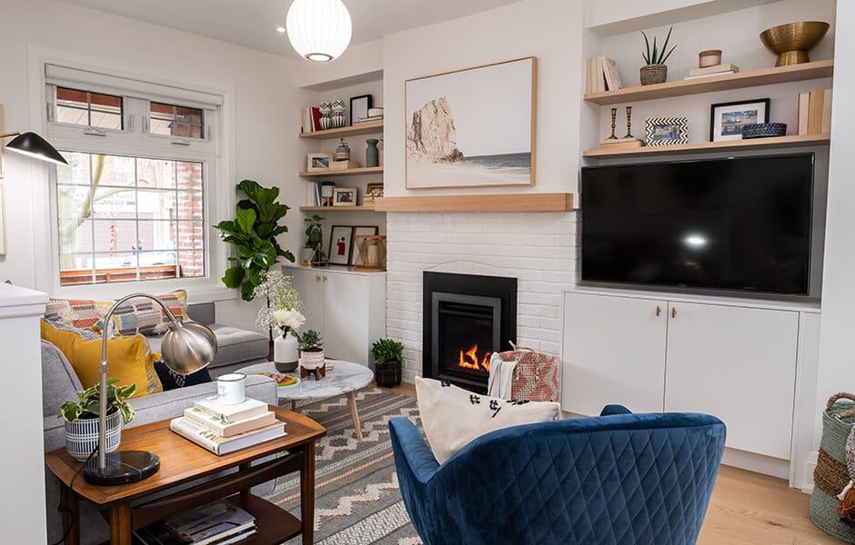 Cozy living room with fireplace, built-in shelves, a blue chair, and neutral decor accents