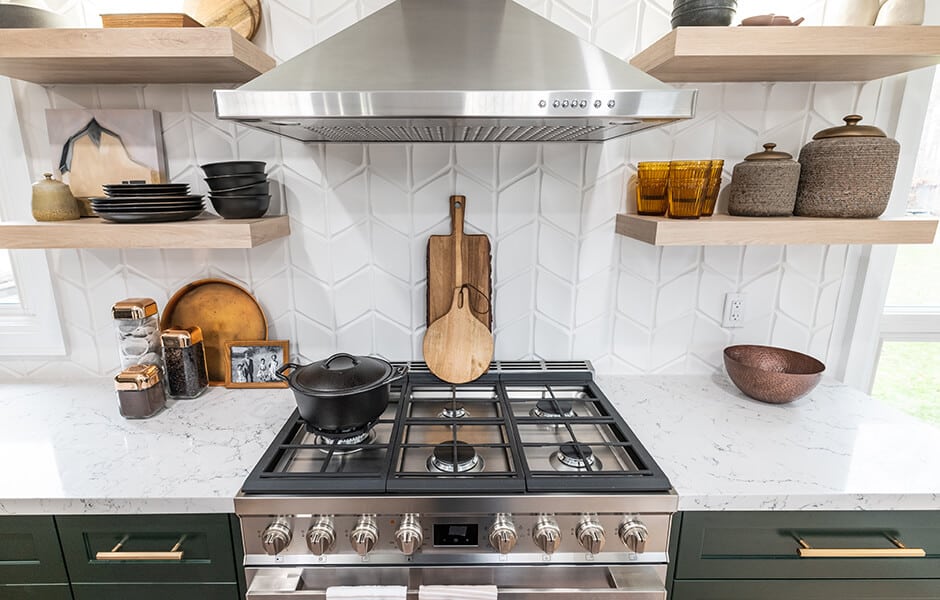 Modern kitchen stove with pot, wooden cutting boards, open shelving, and stainless steel range hood