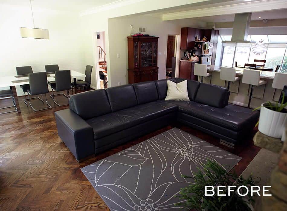 Spacious open-concept living area with black sectional sofa, patterned rug, and dining area