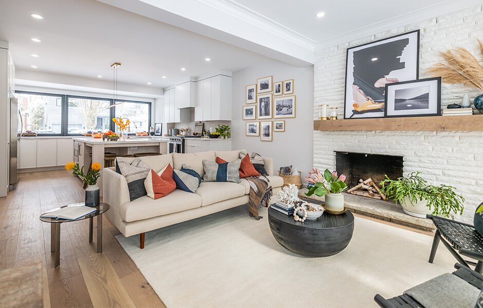 Open-concept living room and kitchen with white cabinetry, and cozy beige sofa