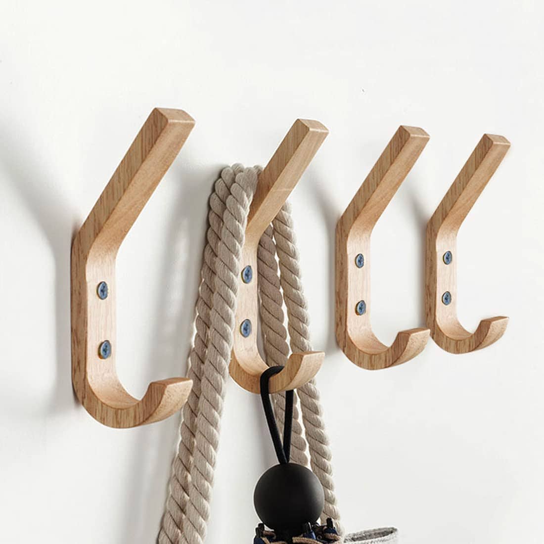 Set of four wooden wall hooks mounted on a white wall, holding a rope and hanging items