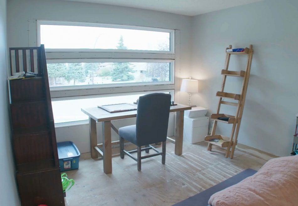 Minimalist office with wooden desk, gray chair, and ladder bookshelf