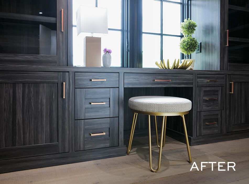 Dark wood built-in desk with gold-accented stool, drawers, and decorative items by a window
