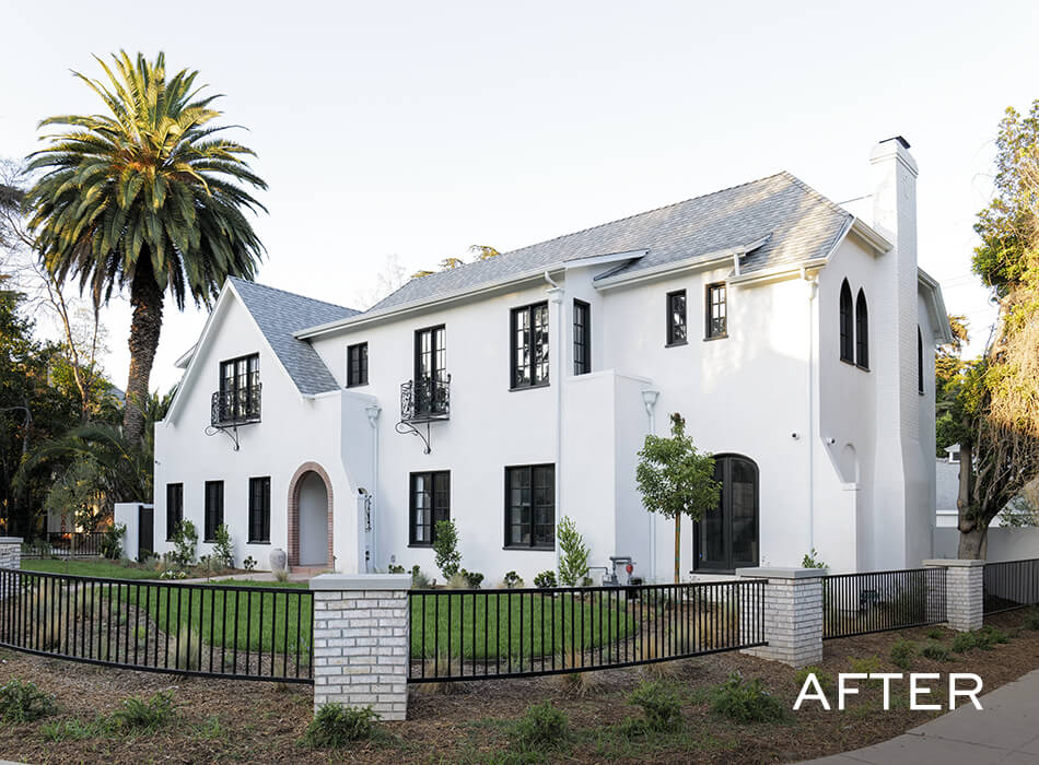 Renovated two-story white house with black trim, arched entryway, and fenced front yard