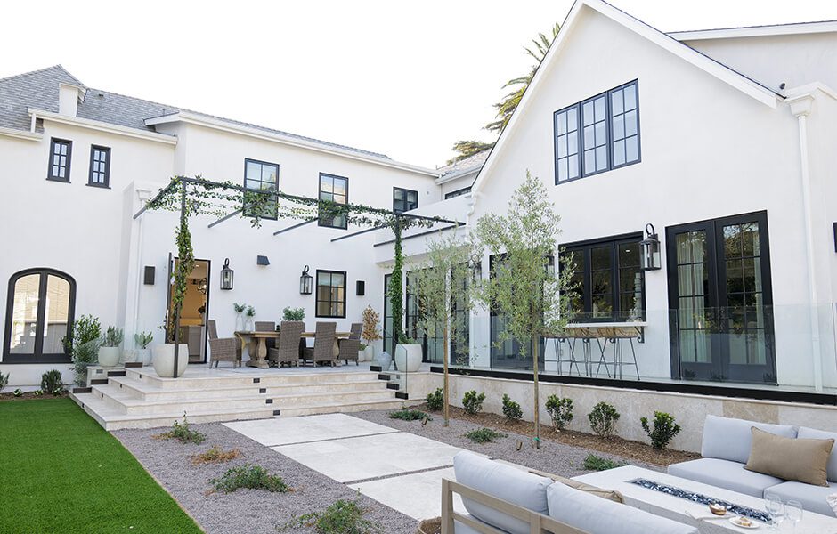 Modern white house with black trim, outdoor dining area, and landscaped patio