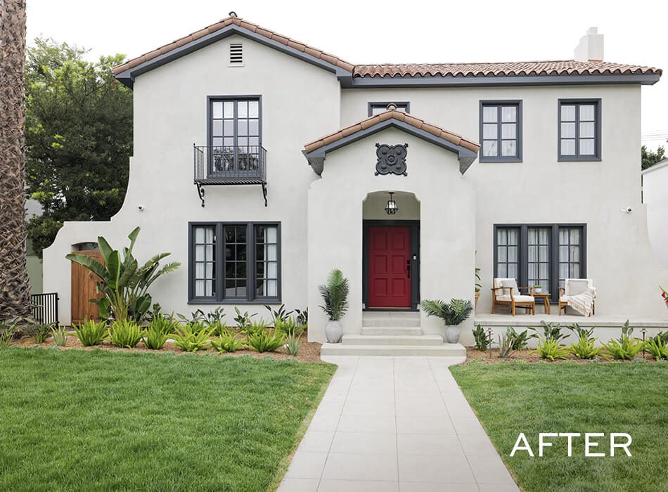 Renovated two-story house with white exterior, red front door, and landscaped front yard