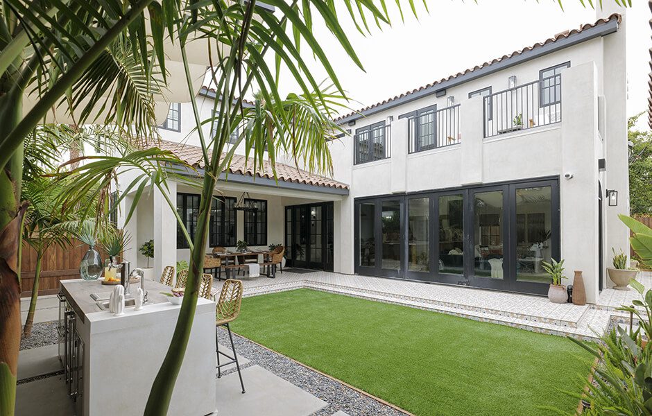 Modern backyard with artificial grass, outdoor kitchen island, and covered dining area