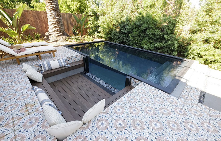Tiled patio with built-in sunken seating next to a raised rectangular pool and lounge chairs