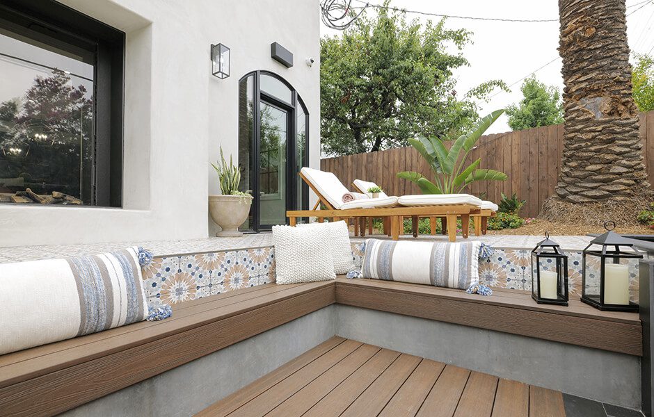 Sunken patio seating area with patterned tile accents, striped pillows, and view of lounge chairs
