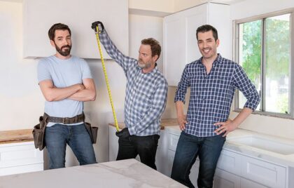 Drew and Jonathan Scott with Rainn Wilson in a kitchen under renovation