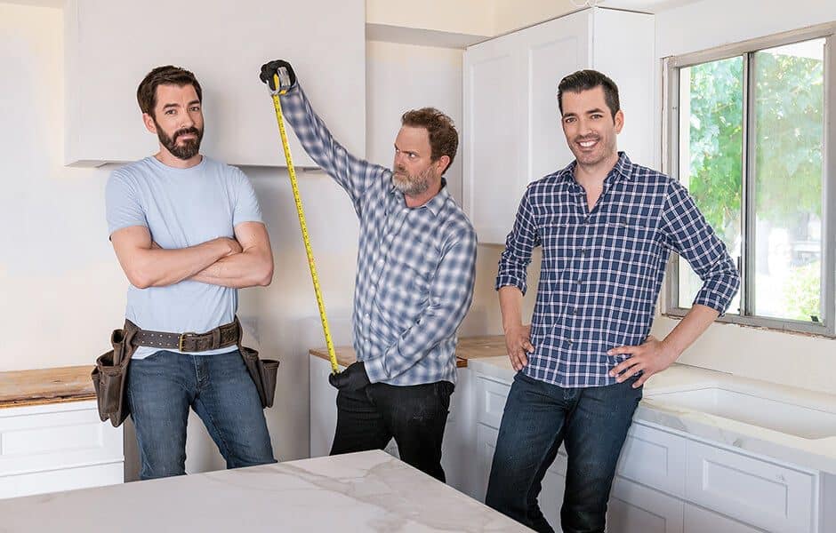 Drew and Jonathan Scott with Rainn Wilson in a kitchen under renovation