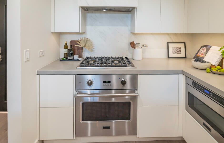 Modern kitchen with stainless steel oven, gas cooktop, and white cabinets