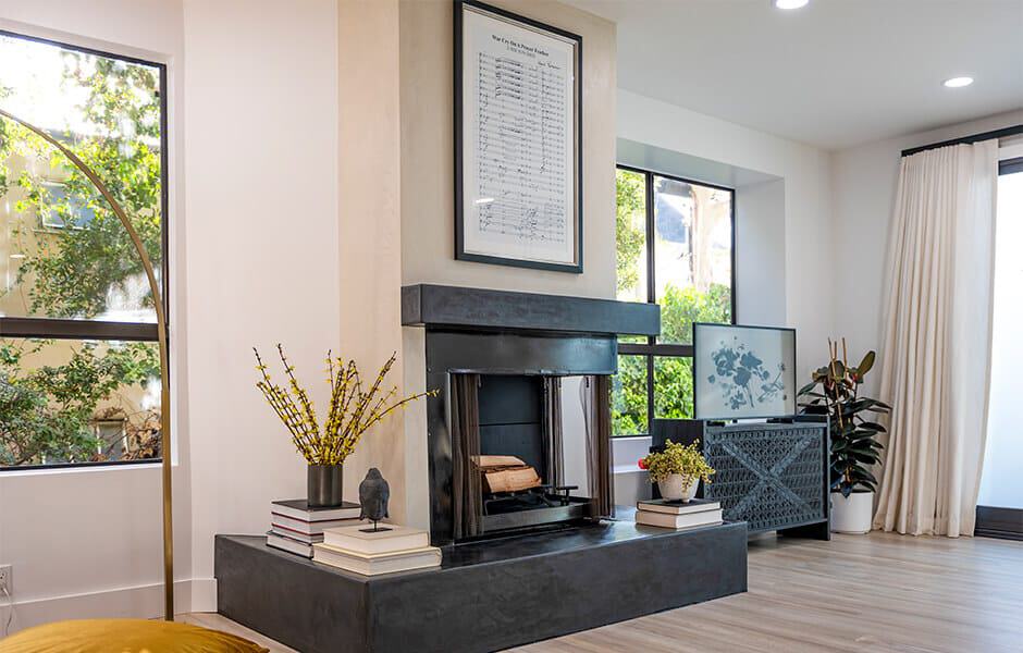 Living room with black fireplace, framed art above, and decorative plants around