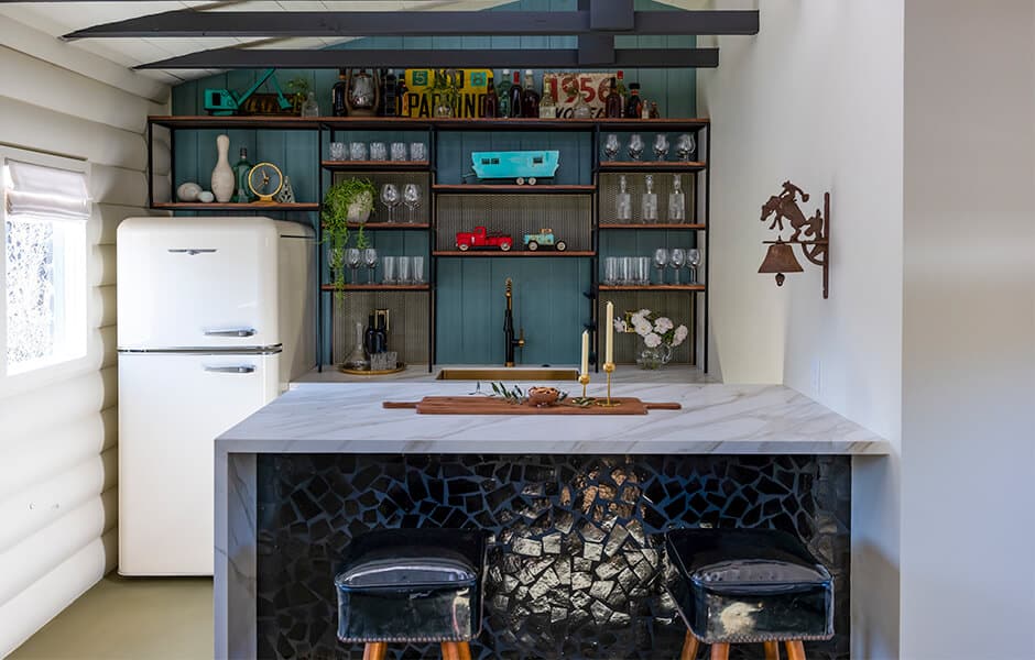 Home bar with marble counter, vintage fridge, open shelves, and decorative accents