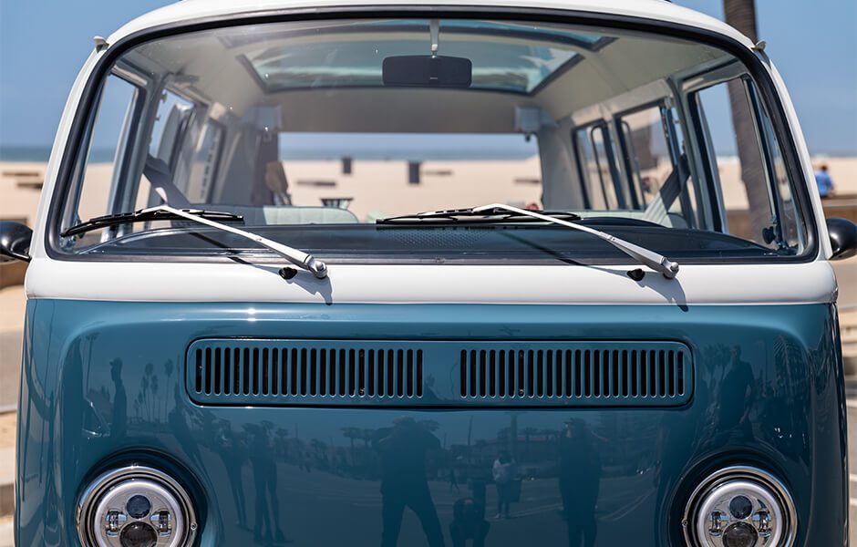Front view of a vintage blue and white Volkswagen van at the beach