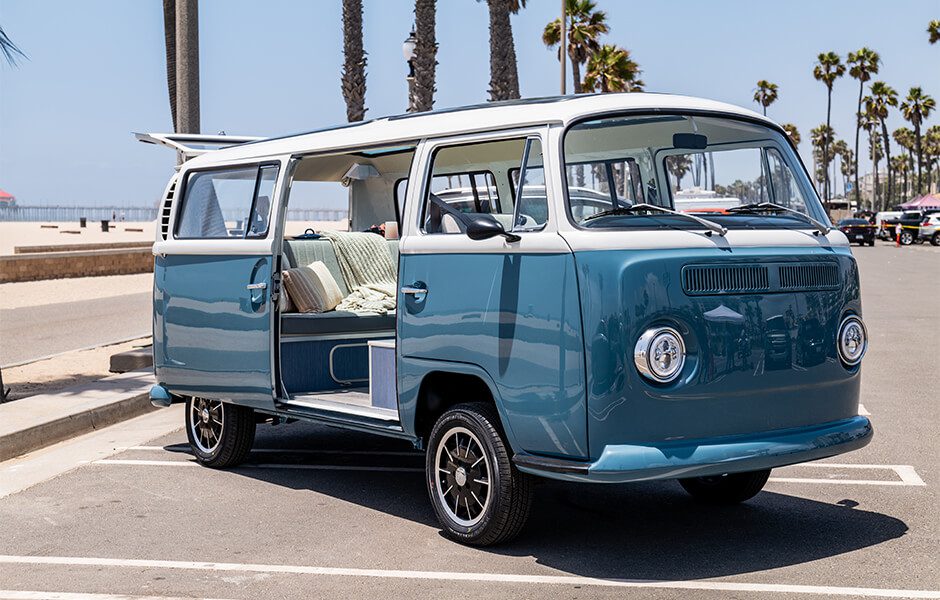 Blue and white vintage Volkswagen van parked by the beach with side door open
