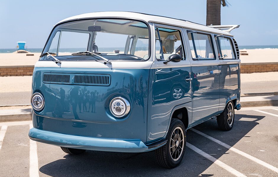 Blue and white vintage Volkswagen van parked near the beach on a sunny day