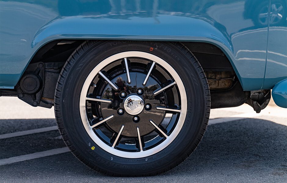 Close-up of a black and silver alloy wheel on a blue vintage Volkswagen van