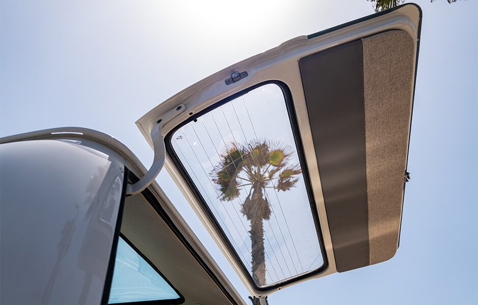View of a raised rear hatch door of a van with a palm tree visible through the window
