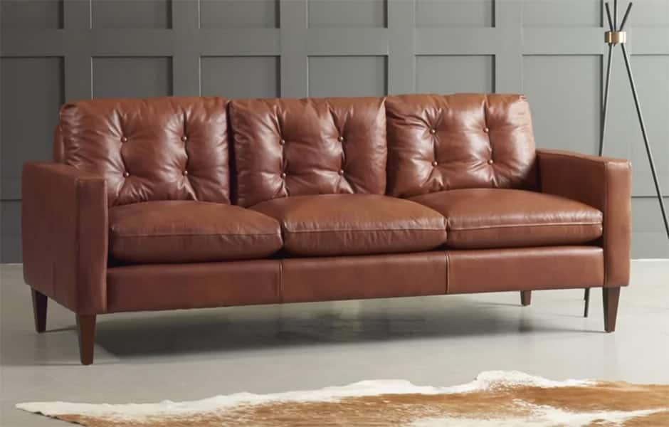 Brown leather tufted sofa with three seat cushions and wooden legs