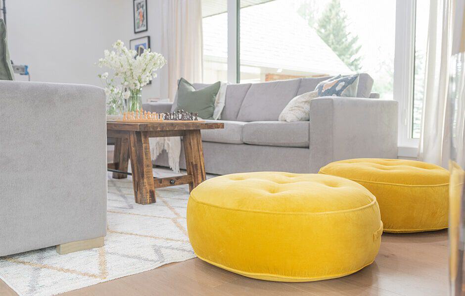 Living room with gray sofa, wooden coffee table, and two bright yellow poufs