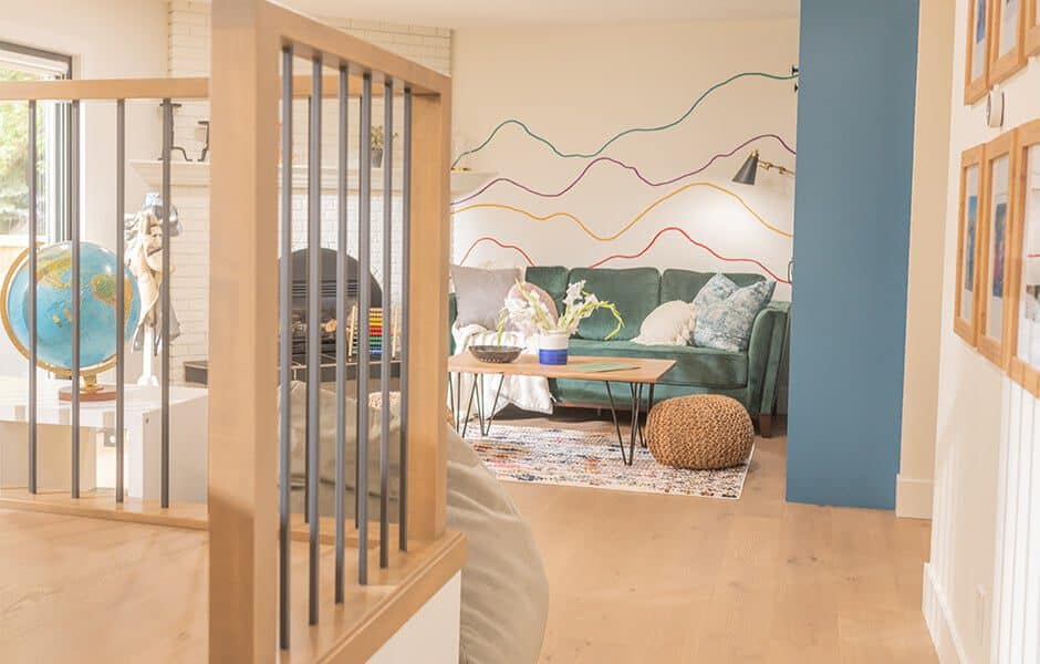 Living room with green sofa, colorful line wall art, wooden coffee table, and woven pouf
