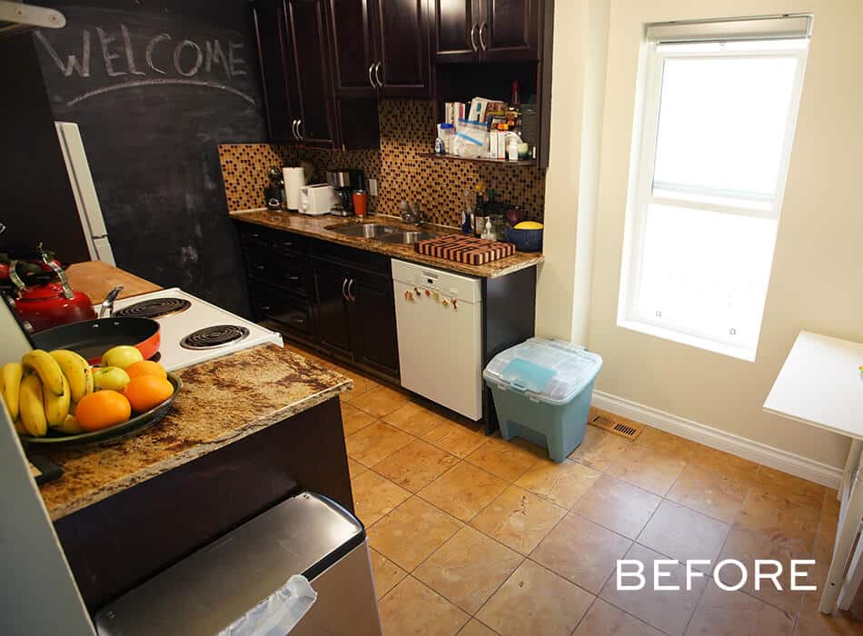 Cluttered kitchen with dark cabinets, tiled backsplash, small appliances, and a window bringing in light