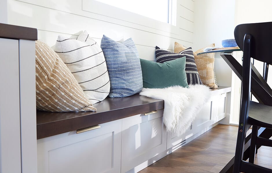 Built-in bench with storage, decorated with colorful throw pillows and a white faux fur blanket