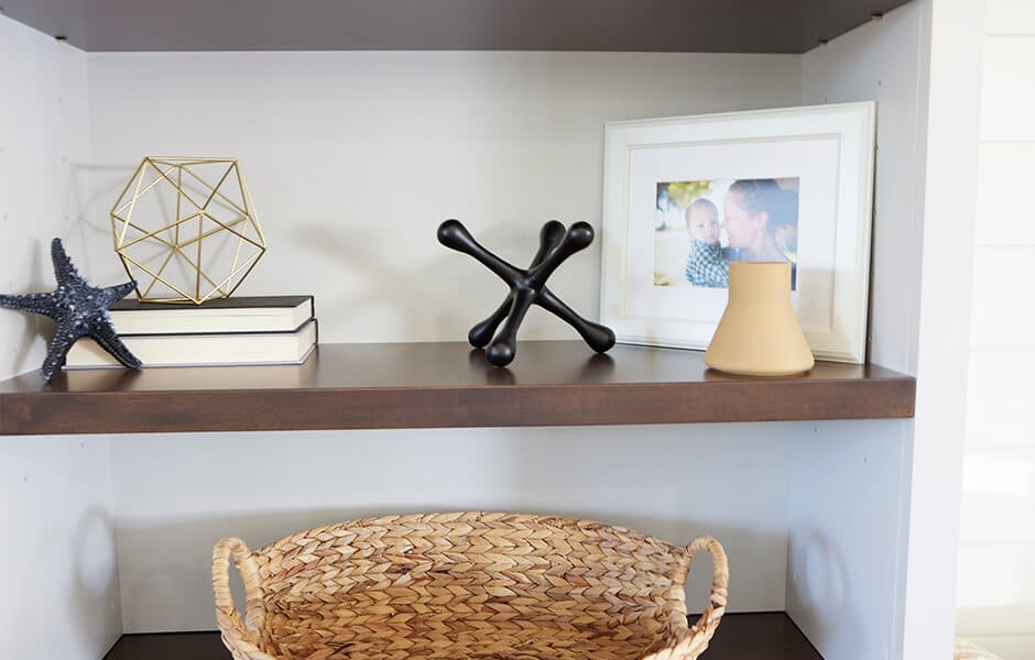 Shelf with books, geometric sculpture, framed photo, vase, and woven basket