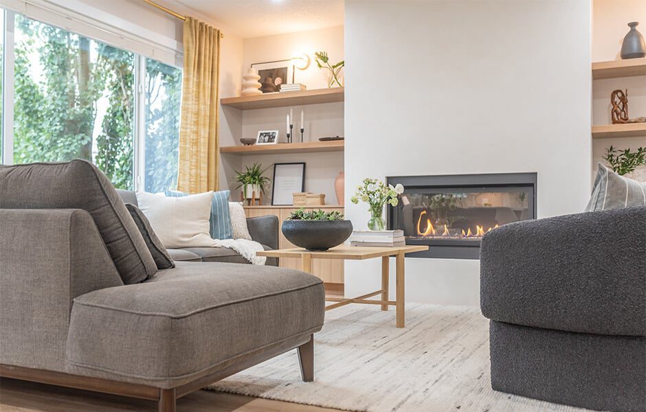 Living room with gray seating, wooden coffee table, built-in shelves, and a modern fireplace
