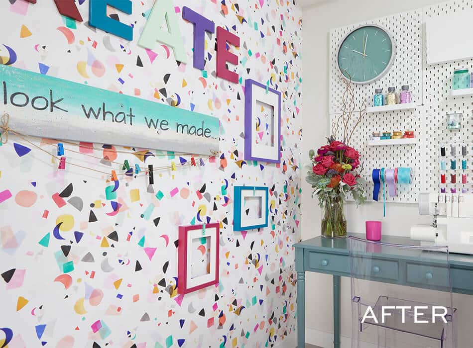 Colorful craft room with patterned wallpaper, decorative frames, organized supplies, and a teal desk with flowers