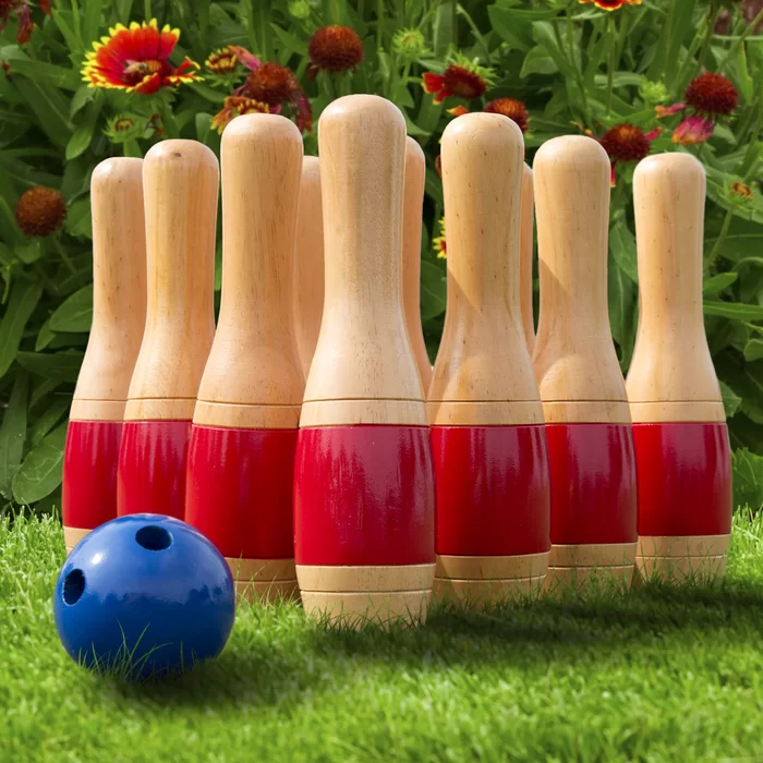 Wooden bowling pins with red stripes and a blue ball on grass