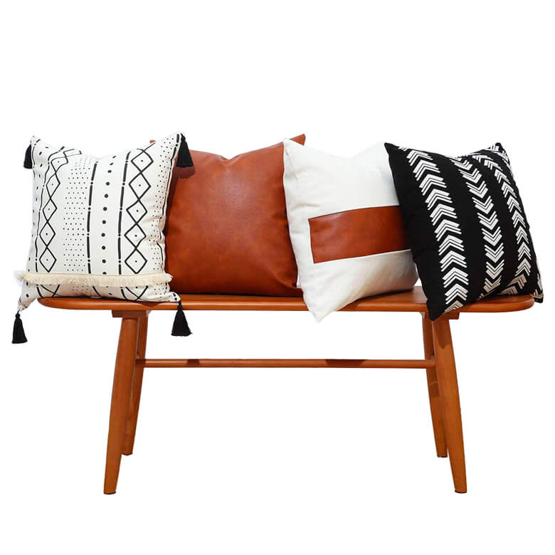 Three pillows on a wooden bench with black and white accents