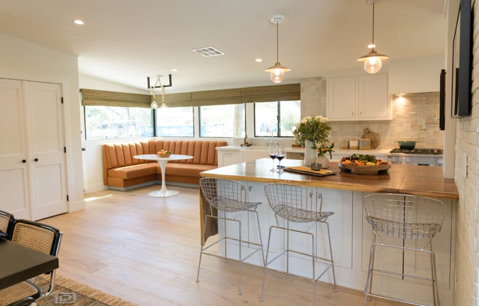 Kitchen with island seating, pendant lights, and built-in dining nook with orange banquette