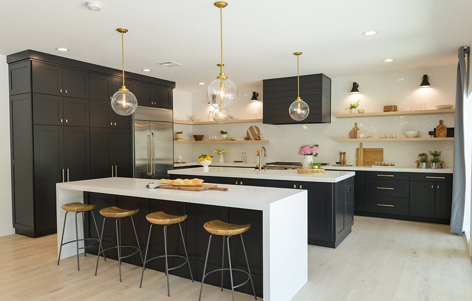 Modern kitchen with black cabinets, white countertops, wood stools, and gold pendant lighting