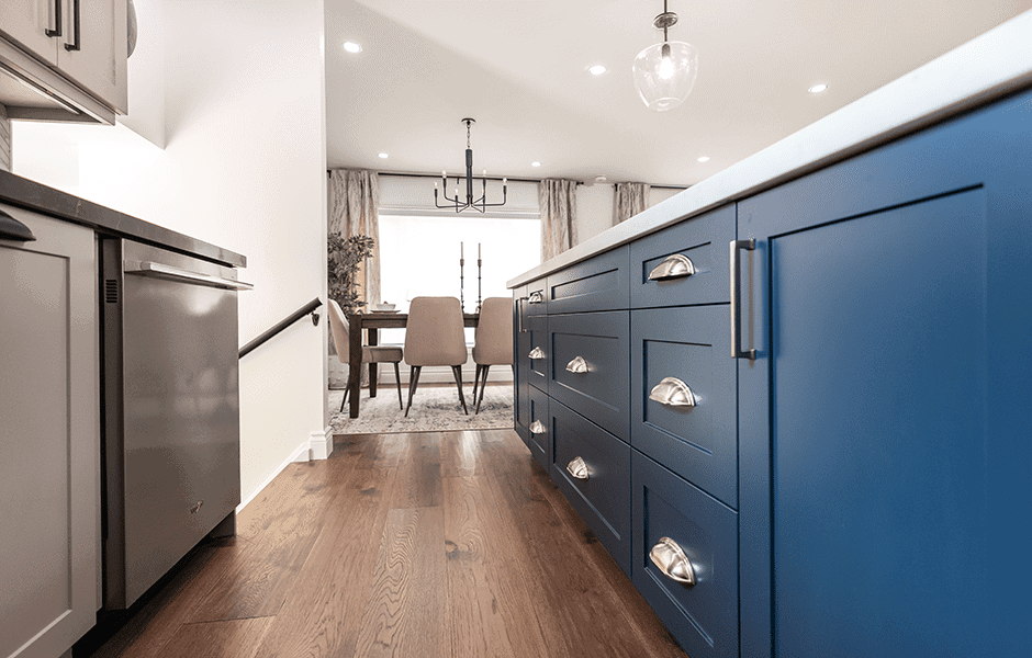 Kitchen with navy blue island cabinets, stainless steel hardware, and view into dining area