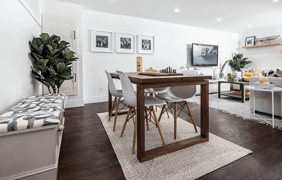 Modern living space with wooden game table, white chairs, wall art, and cozy seating area