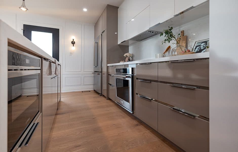 Sleek modern kitchen with glossy taupe and white cabinets, built-in appliances, and wood flooring