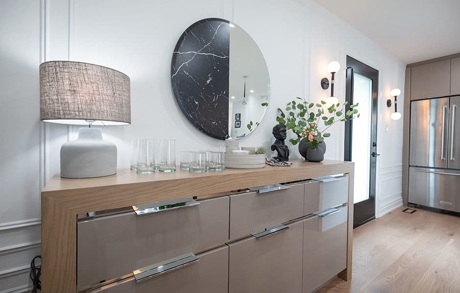 Modern sideboard with glossy drawers, decorative round mirrors, a lamp, and plants